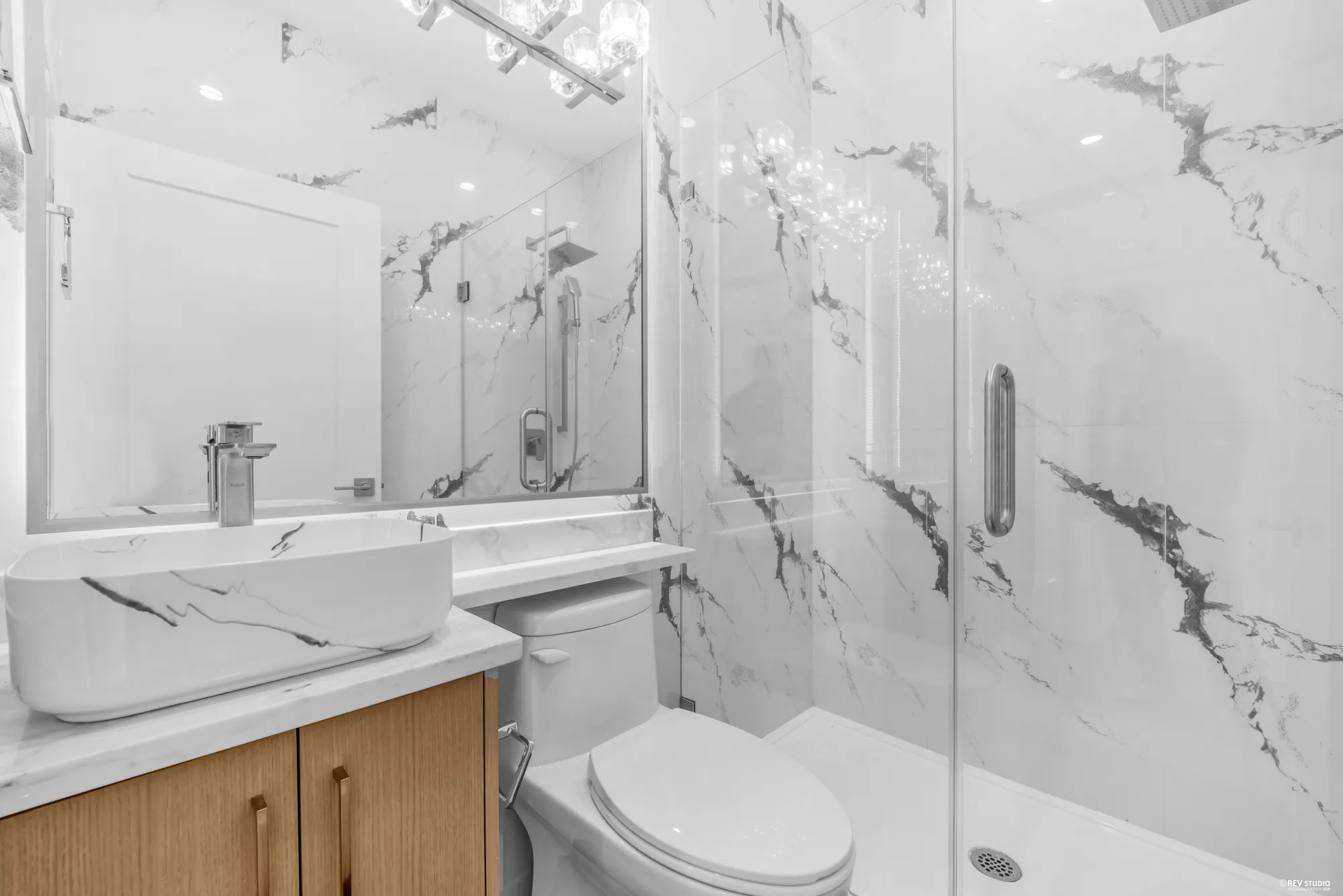 Bathroom with a marble-look shower surround and wood vanity
