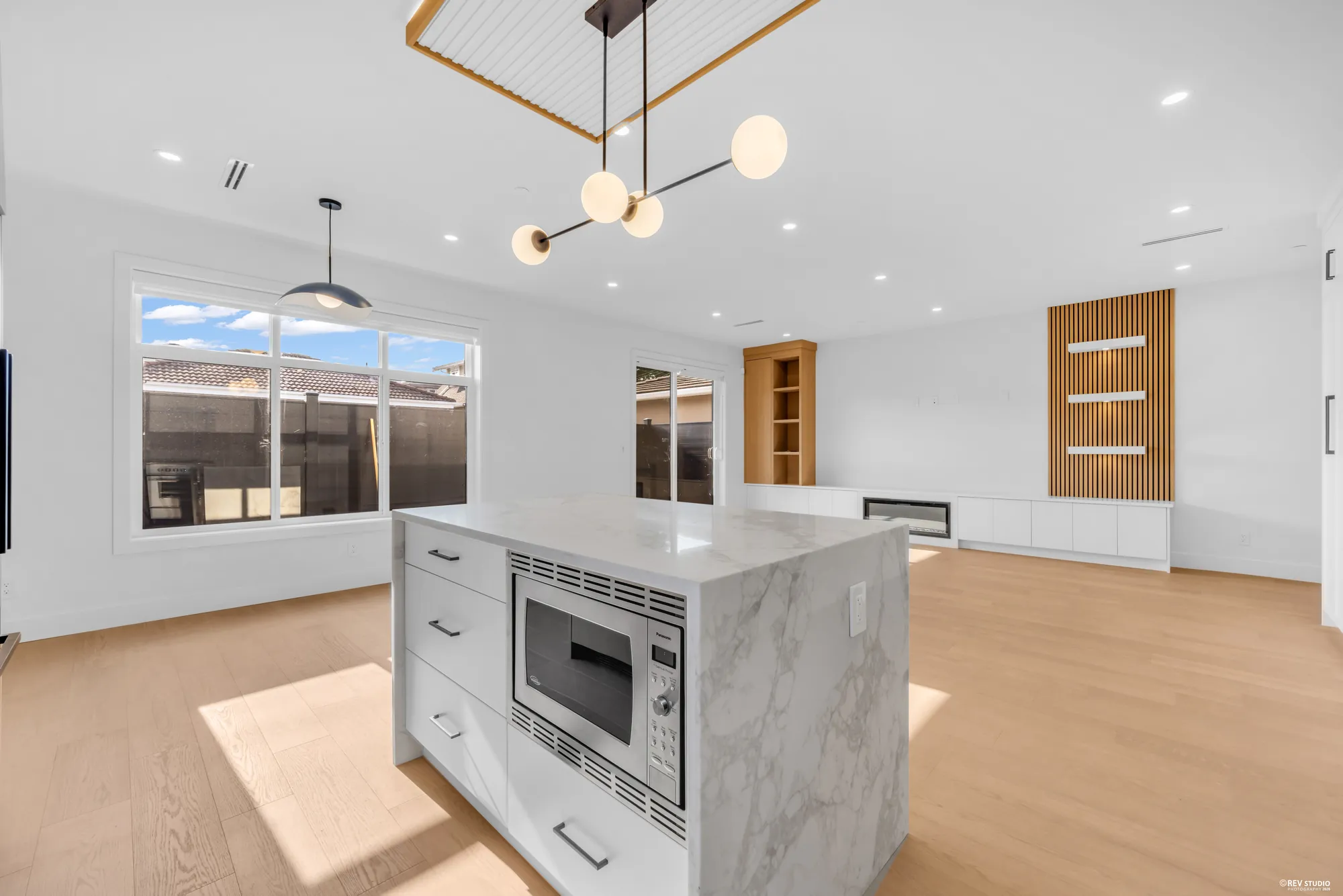 The living room of 2-6388 Argyle Street, nineteen feet across and glazed along one wall to the patio